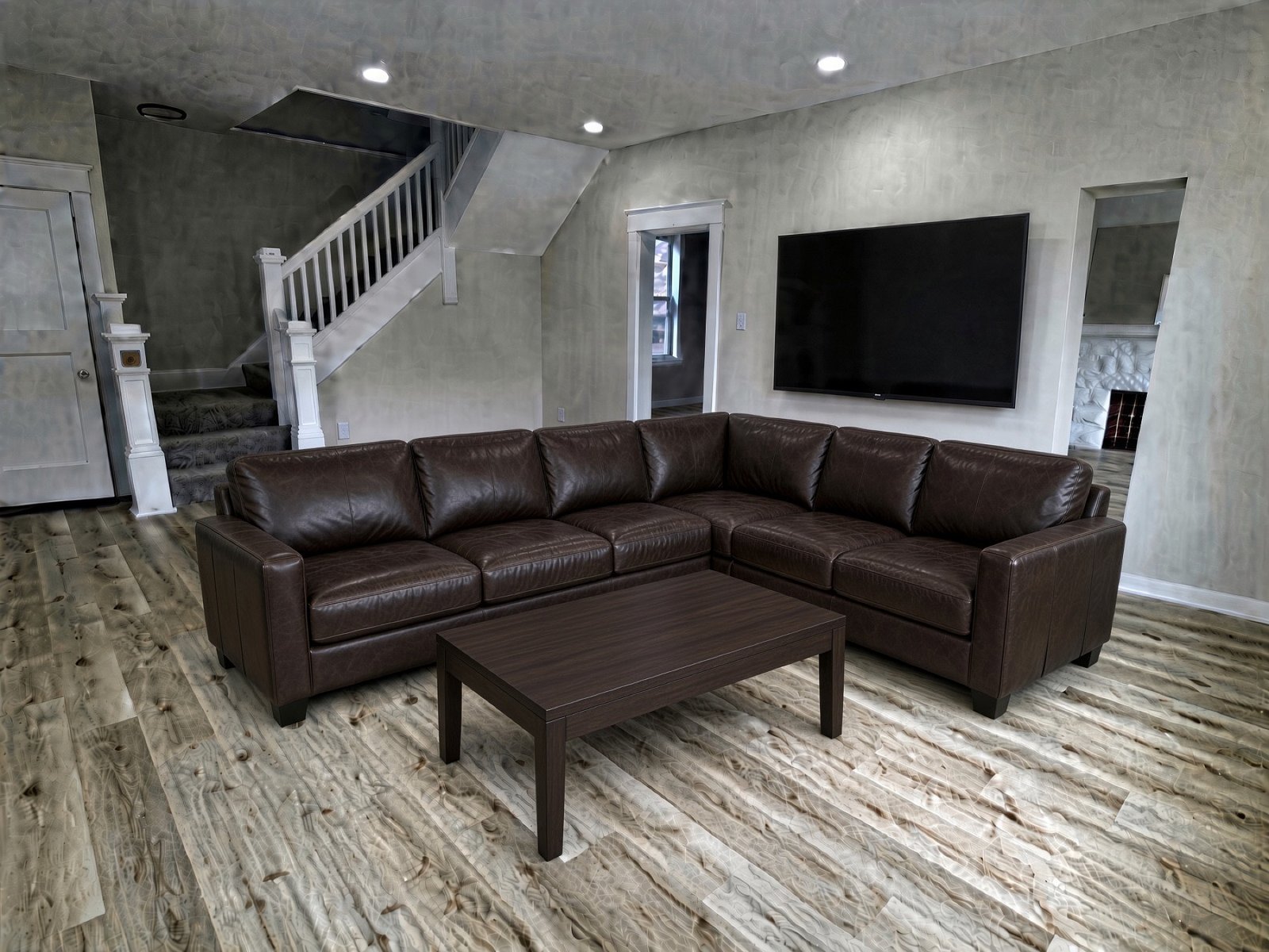 Living room with a brown leather sectional, coffee table, and wall-mounted television